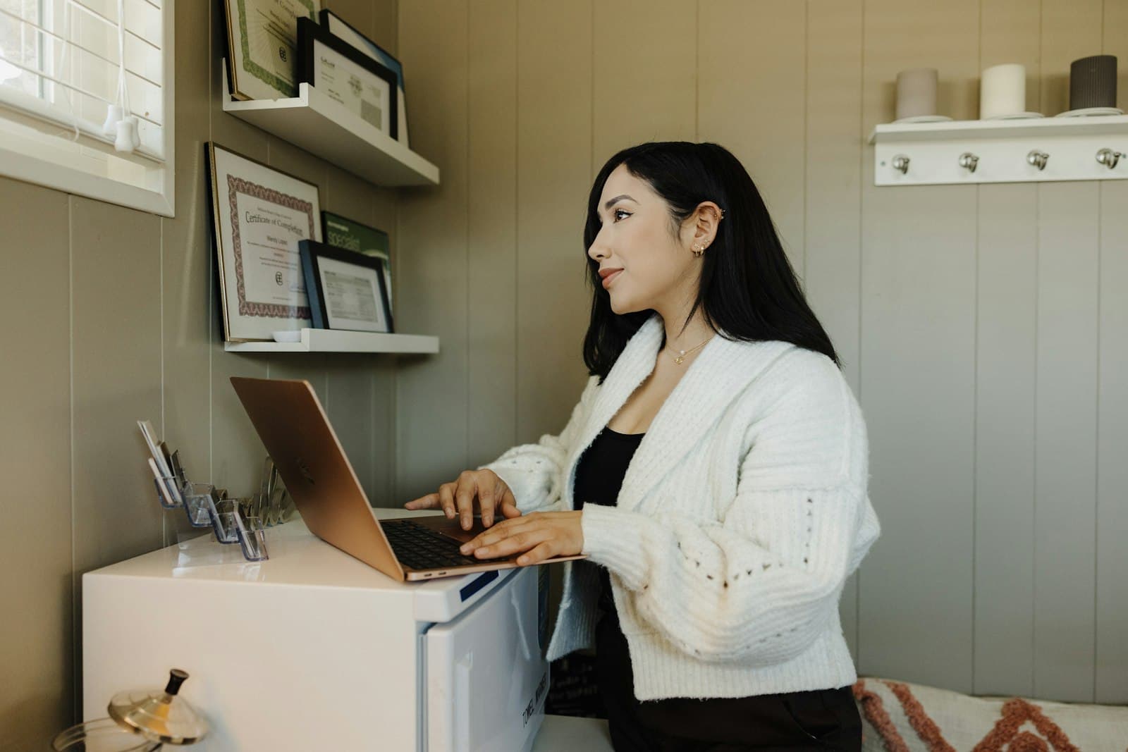 En kvinde arbejder på sin bærbare computer i et lille, lyst lokale.